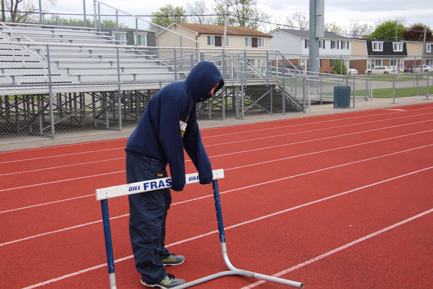 As part of their jobs with being on the track team, Ben Clark sets up the hurdles for the 400 meter hurdle event. 