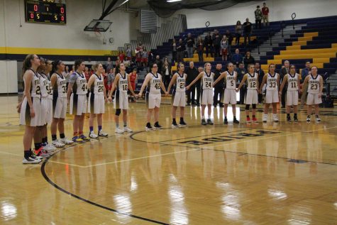 The Lady Ramblers stand together as the National Anthem plays over the gym.